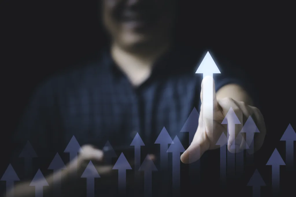 Homem ao fundo com muitas setas apontadas para cima na frente dele, imagem que pode significar vantagem, vantajoso, crescimento.